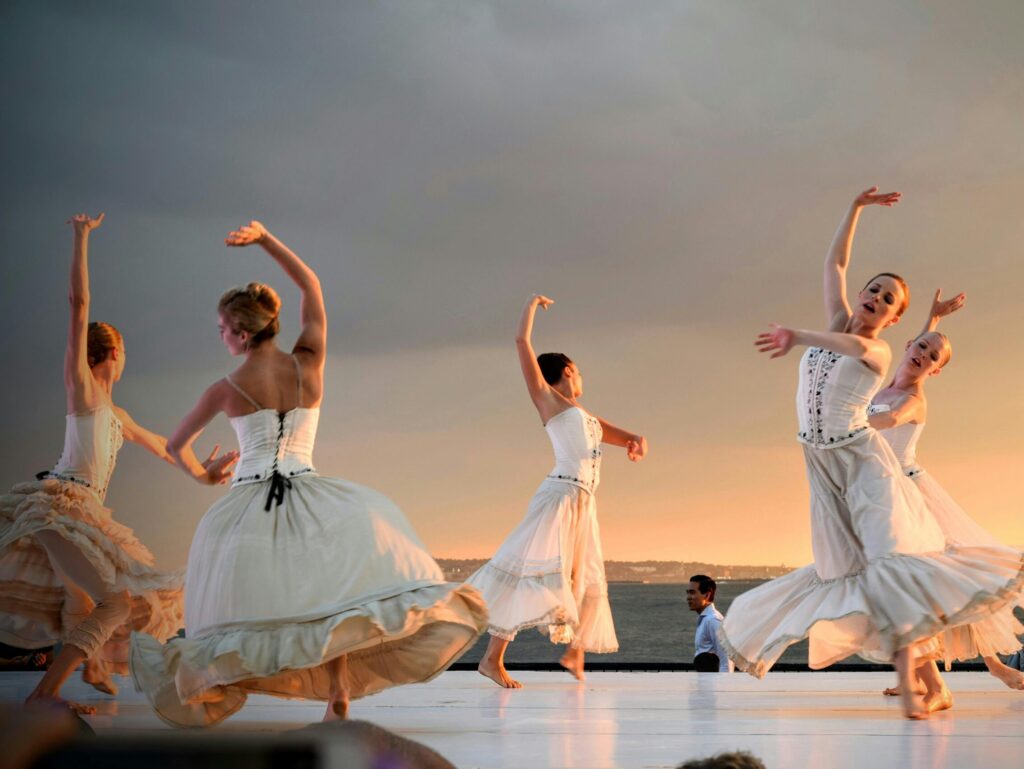 Elegant ballerinas performing a captivating dance at sunset outdoors.