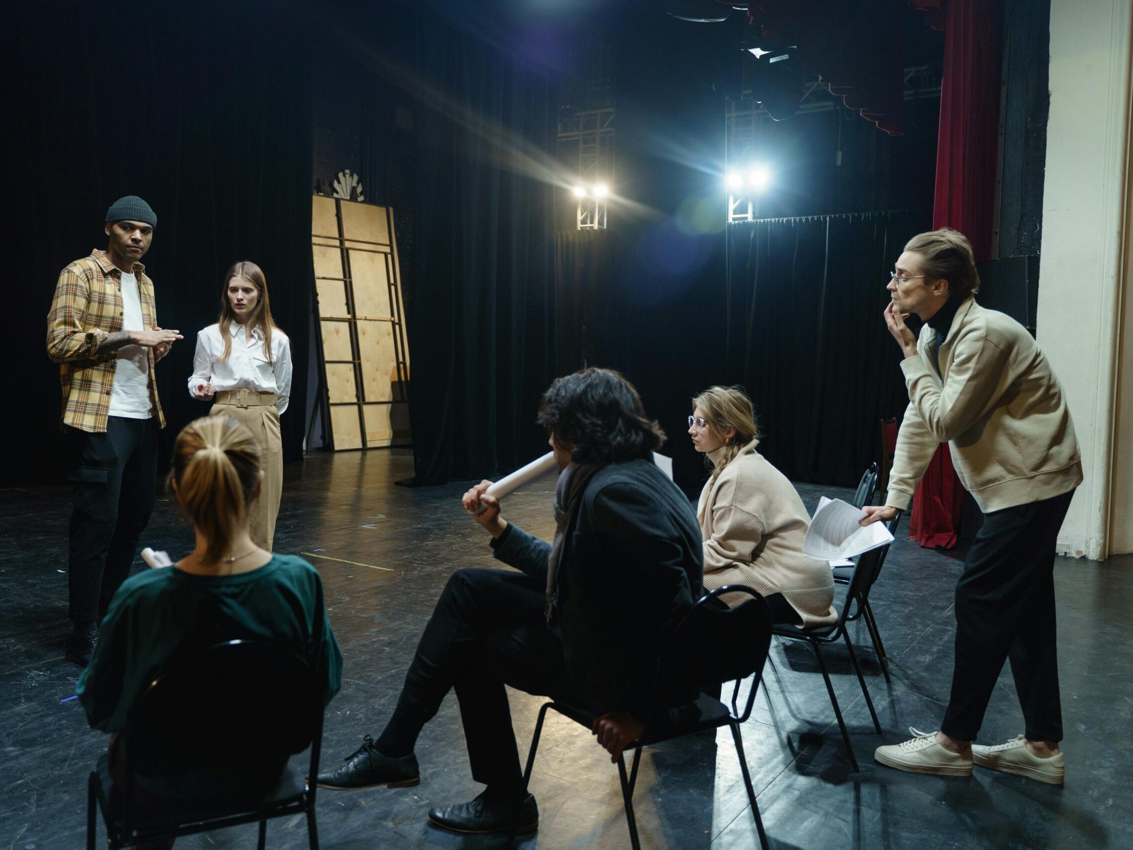 Actors rehearsing on stage with director's guidance in a theater for a live performance.